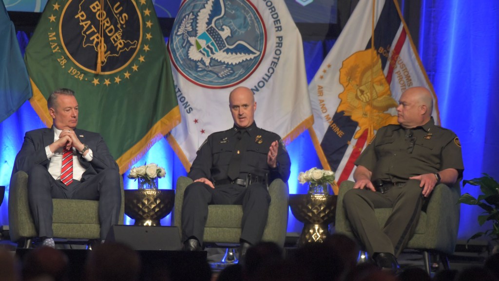 todd lyons, Chris Holtzer and John Morris sit in chairs on a stage