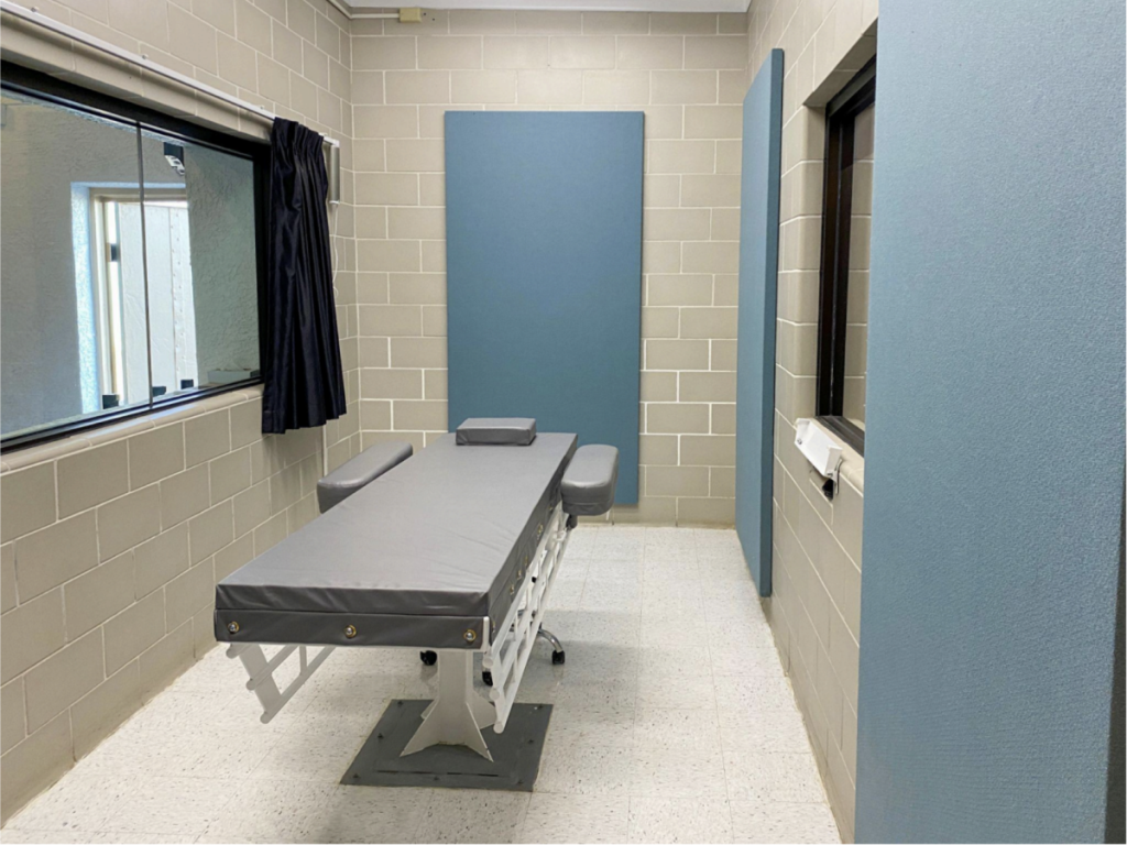 a narrow, austere room with a window and a bed