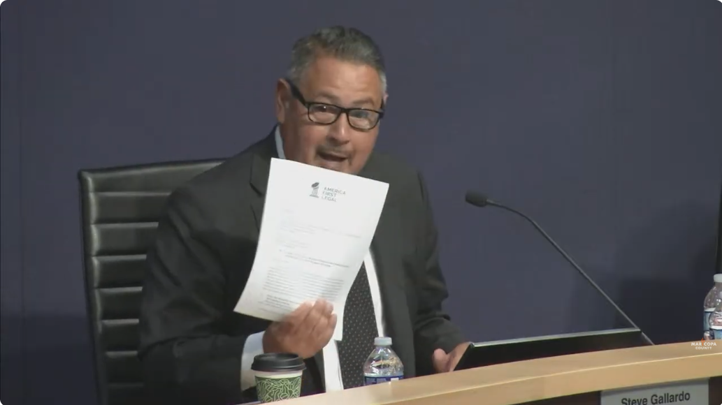 Steve Gallardo holds up a letter during a meeting