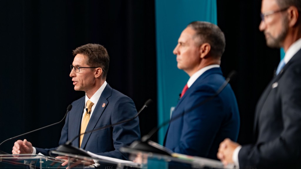 joseph chaplik, jay feely and john trobough at a debate