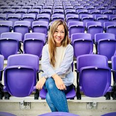 Dr. Joanna Fong-Isariyawongse sitting in a sports stadium seat