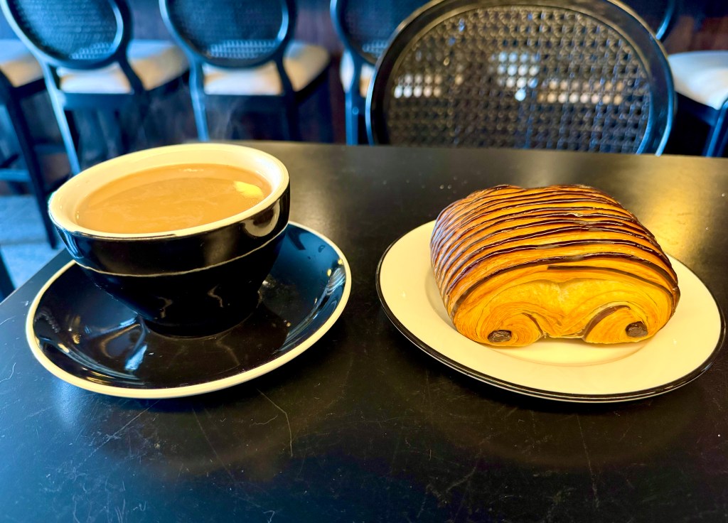 A cafe au lait and pain au chocolat on a table at Brasserie Melrose.