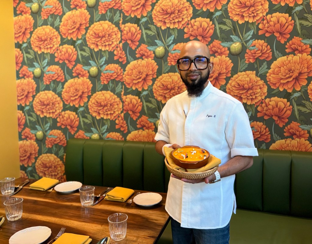Nadu chef Pujan Sarkar poses with a desert in the restaurant's colorful dining room.