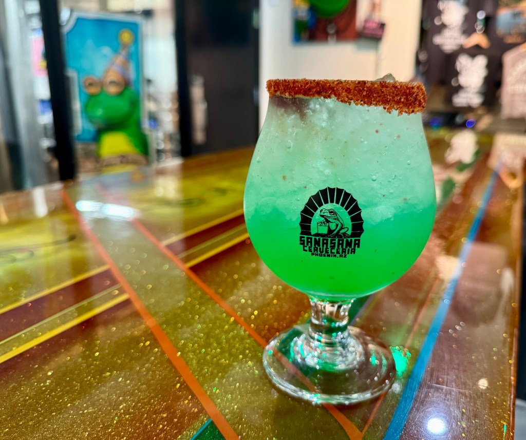 A glass of Sana Sana’s green Copa Mundial cucumber-lime seltzer with a Tajin rim.