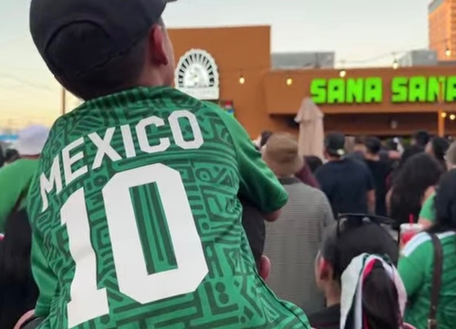 A boy sits on a man's shoulders to watch a Mexico match during the World Cup at Sana Sana Cerveceria.