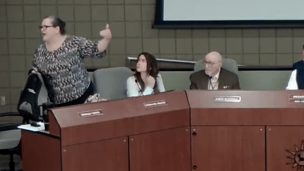 kim fisher yells at someone in a crowd at a school board meeting