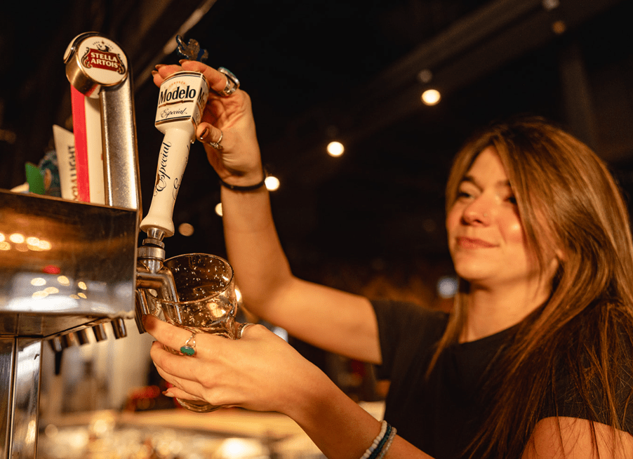 A woman bartender pours Modelo into a pint glass at Thirsty Lion.