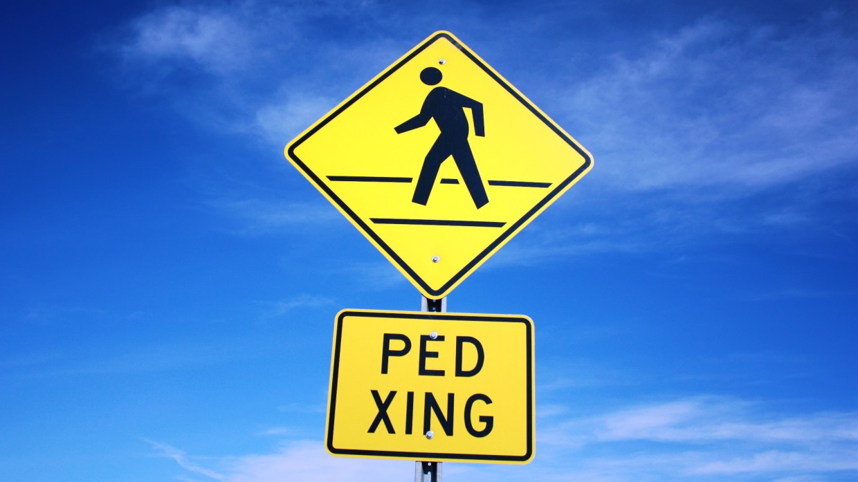 a yellow pedestrian crossing sign