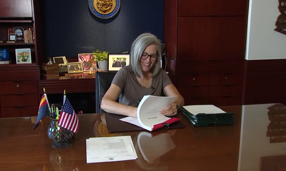 Gov. Katie Hobbs signs state budget at her desk.
