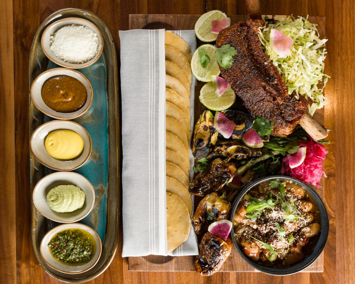 A large taco board and sauces on a table.