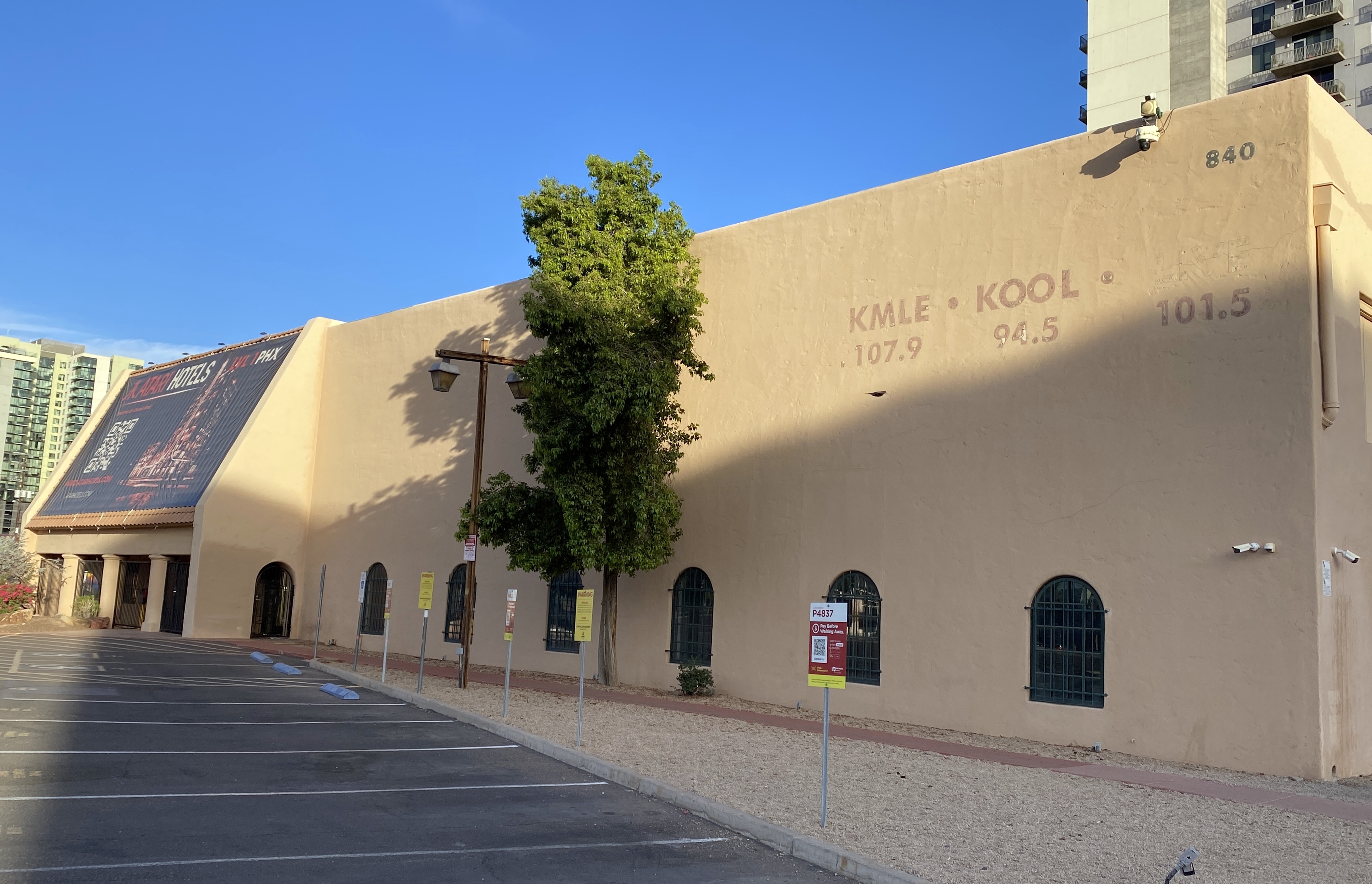 The former KOY Building in downtown Phoenix with faded signs for radio stations KMLE, KOOL and 101.5 visible on its exterior and an Atari Hotel banner hanging near the entrance.