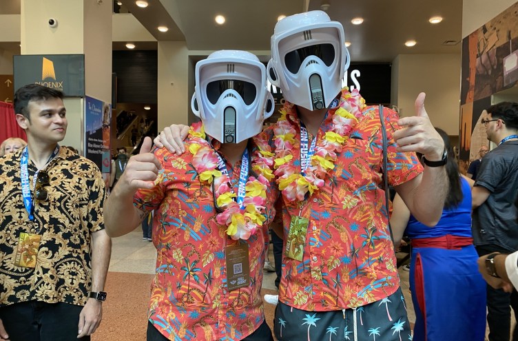 Two Phoenix Fan Fusion attendees wearing scout trooper helmets, Hawaiian shirts and flower leis pose inside the Phoenix Convention Center during the annual pop culture convention.