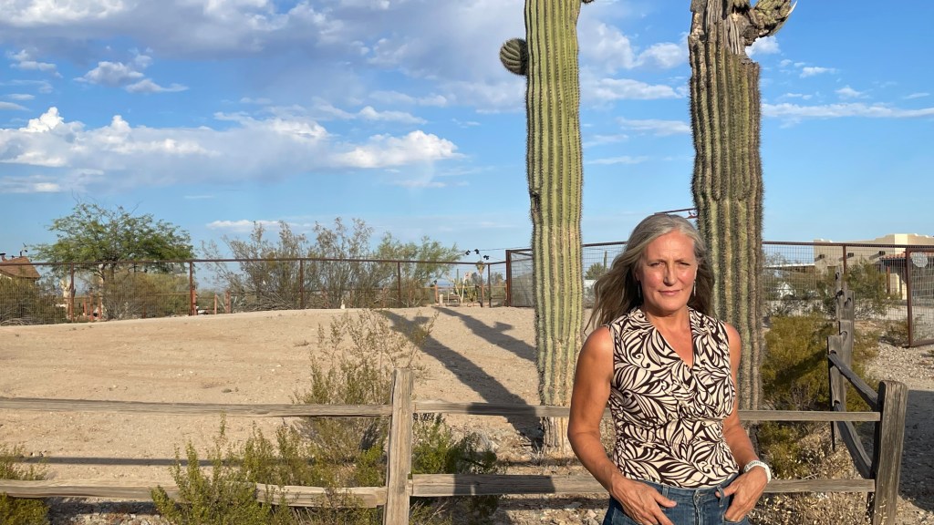 carolyn button stands in front of a desert landscape