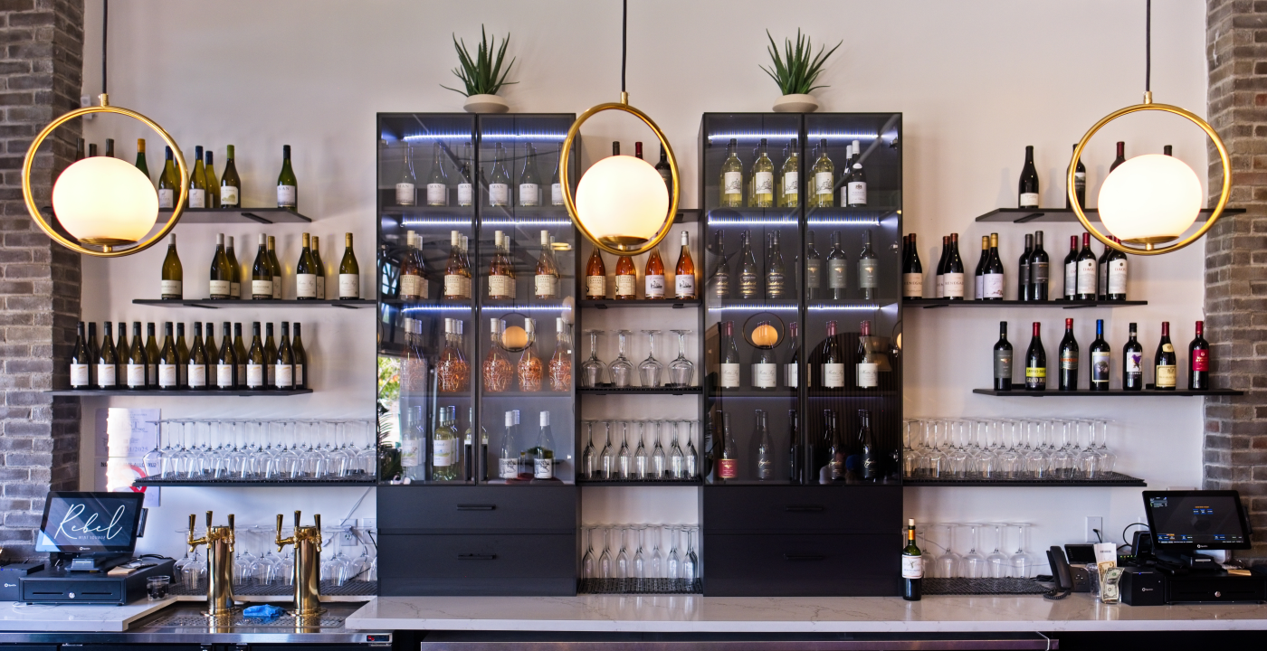 A view of the modern bar at Rebel Wine Lounge, stocked with wine bottles and glasses.