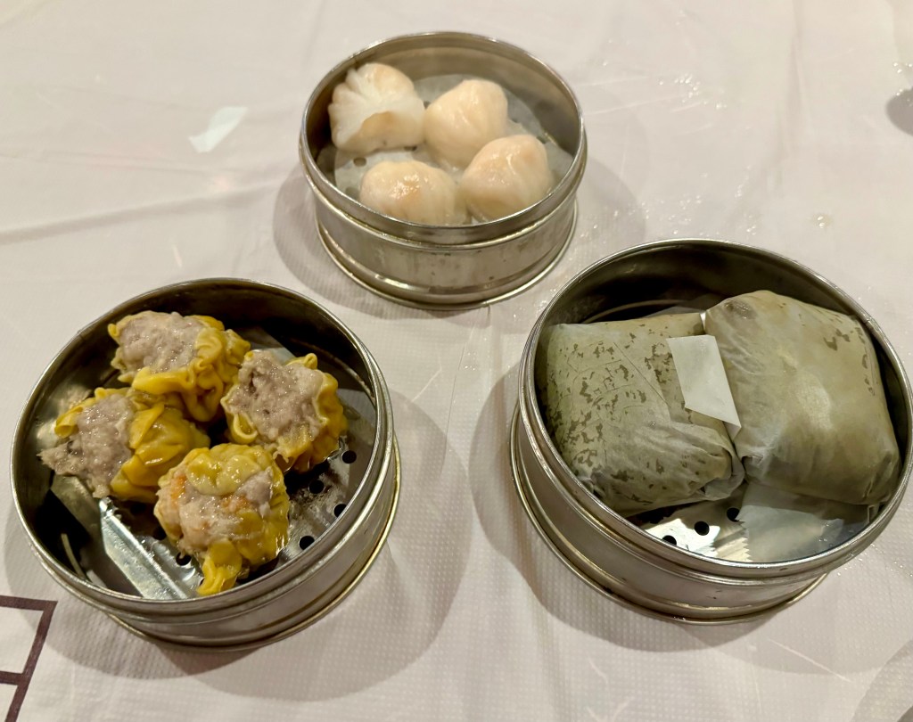 Three steamer baskets sit on a table at Great Wall Cuisine, holding dumplings and sticky rice.