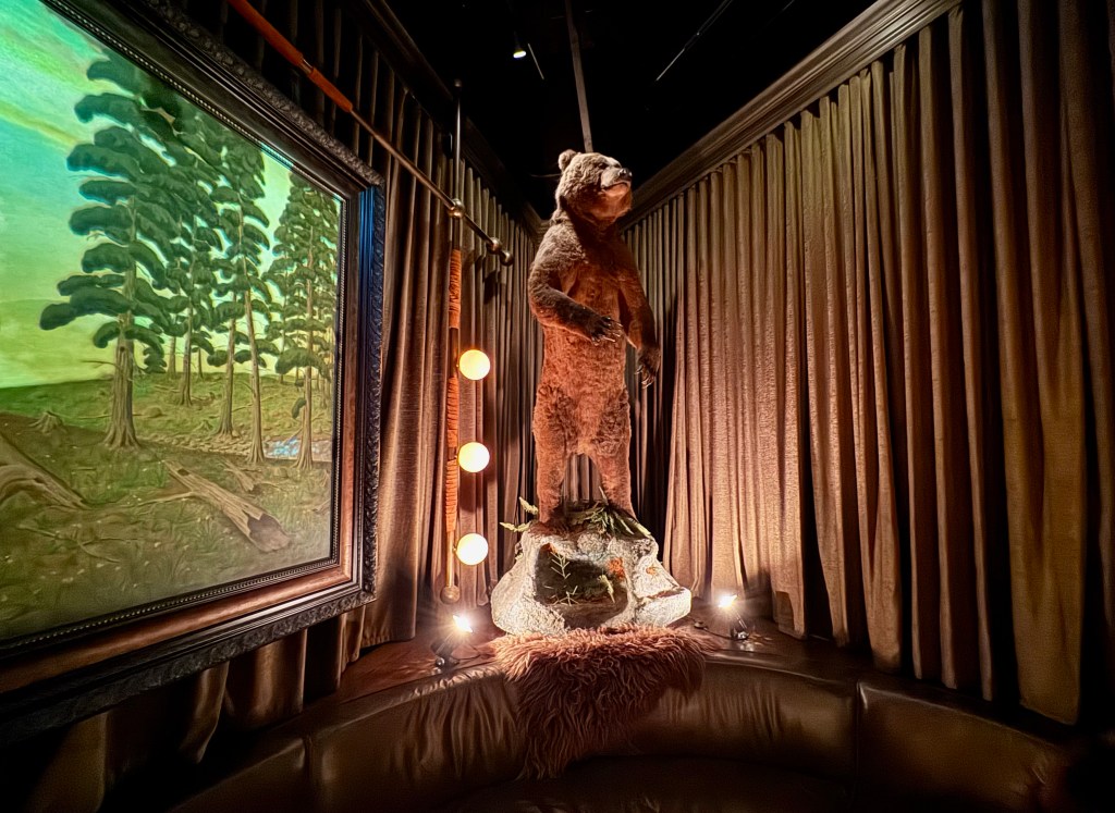 A taxidermied grizzly bear towers over a booth at Trophy Room.