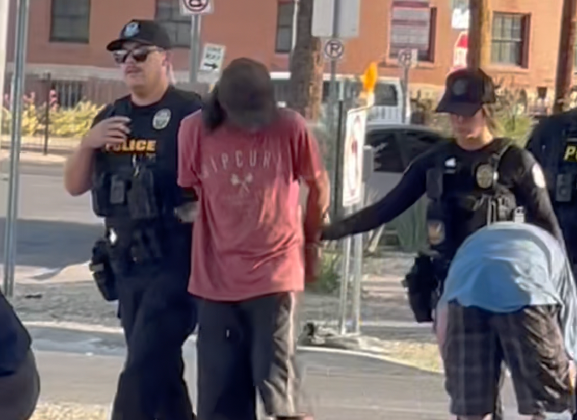 A homeless man is arrested by police officers