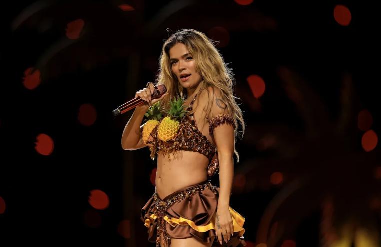 Karol G performs onstage wearing a pineapple-inspired costume during a concert.