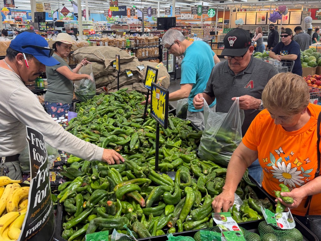 Food City shoppers fill produce bags with green chiles.