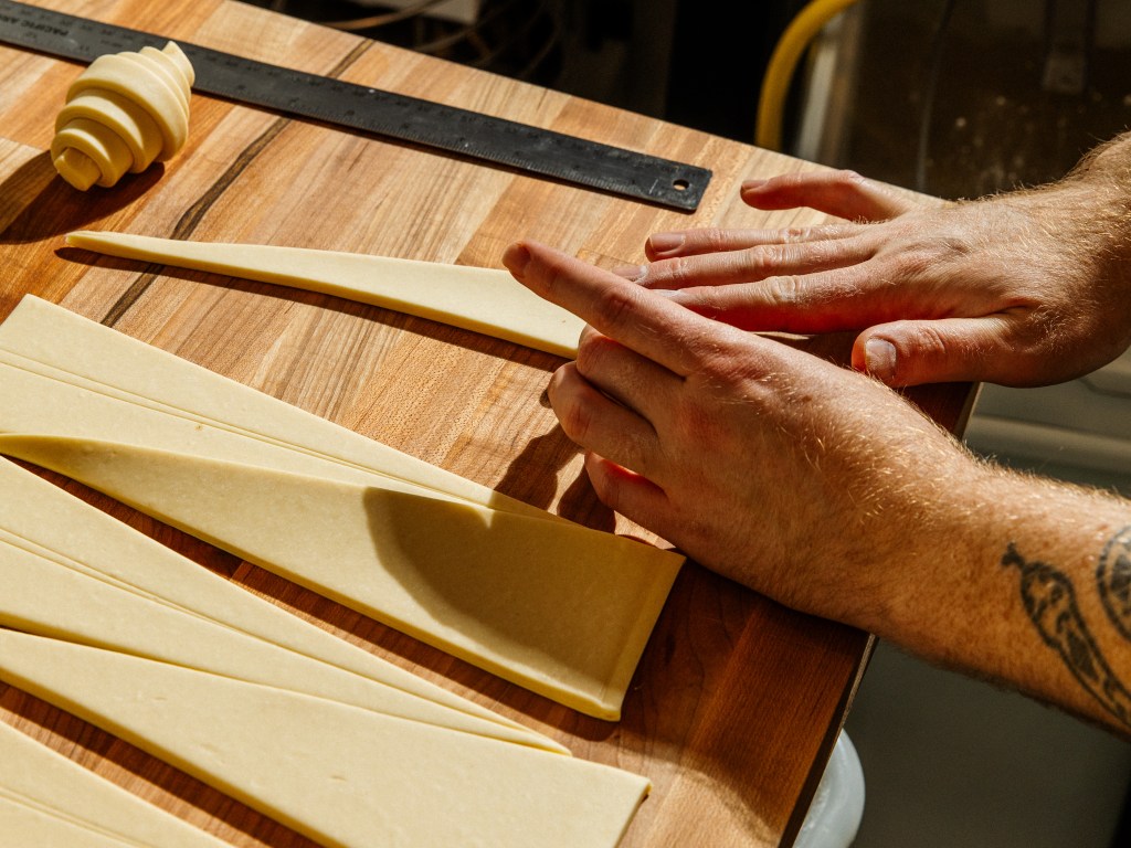 A baker rolls croissant dough.