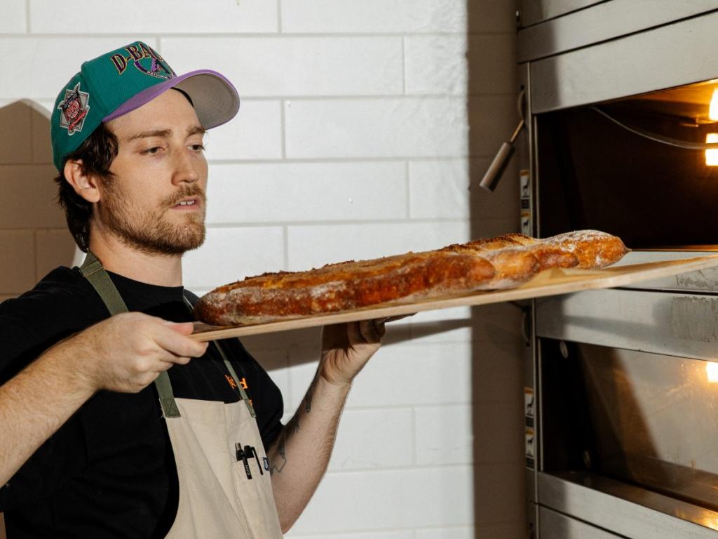 Baker Ryan Spracale checks baguettes he's pulled from a bread oven at Moxie Coffee Co.