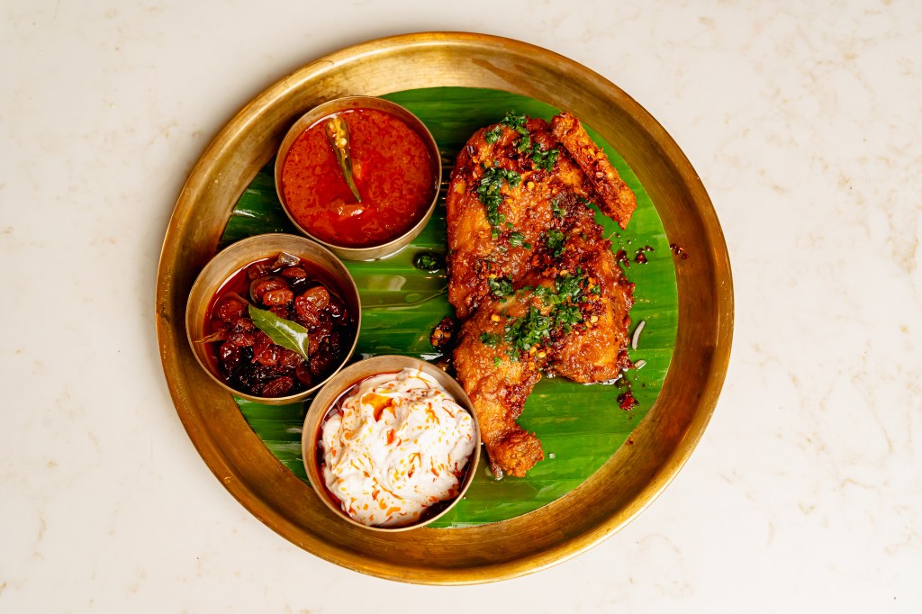A platter with a Kerala-style half fried chicken and condiments.