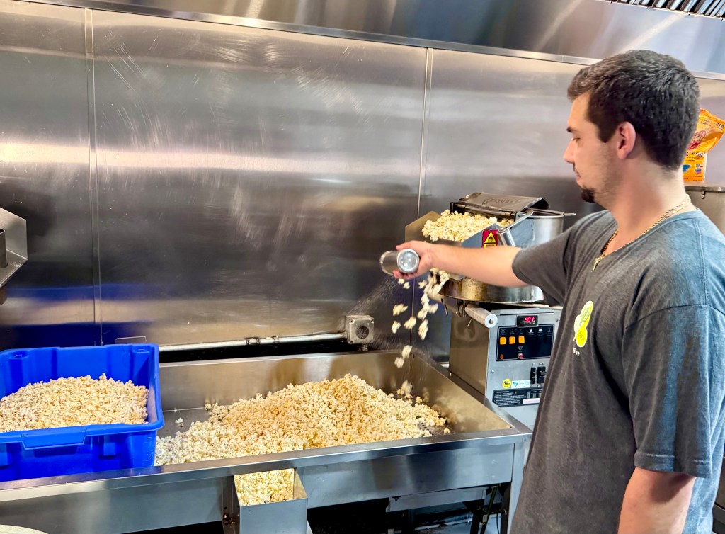 A man seasons kettle corn with salt.