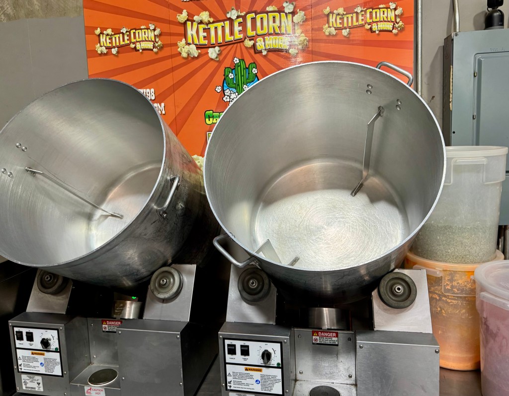 Two large popcorn tumblers on a table with spices and seasonings at Cactus Corn.