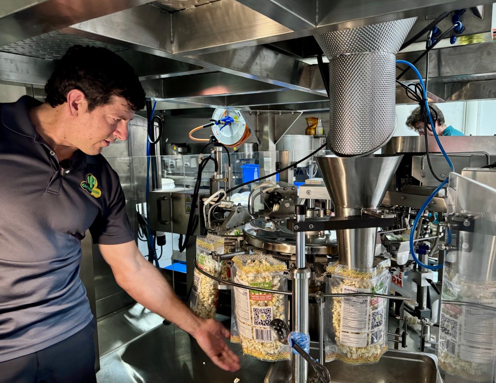 Owner Chris Levandowski taps bags of popcorn before they're sealed.