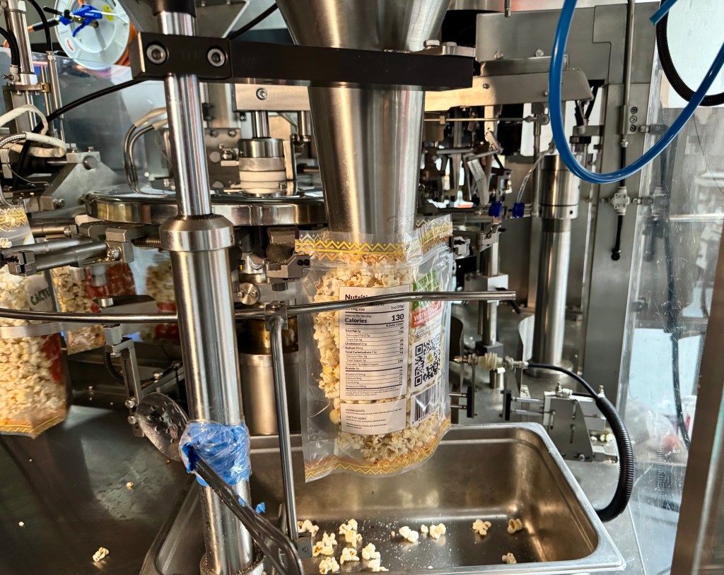 A machine fills bags with Cactus Corn popcorn.