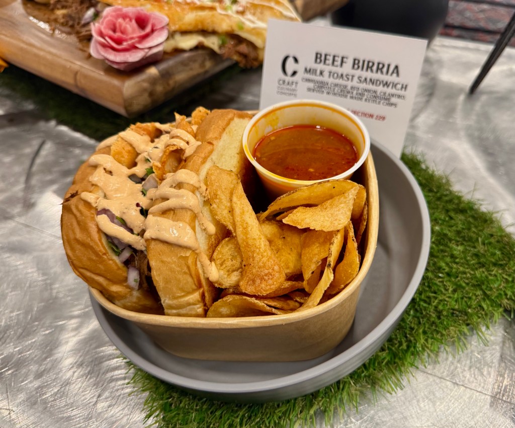 A beef birria milk toast sandwich with consume and kettle chips.