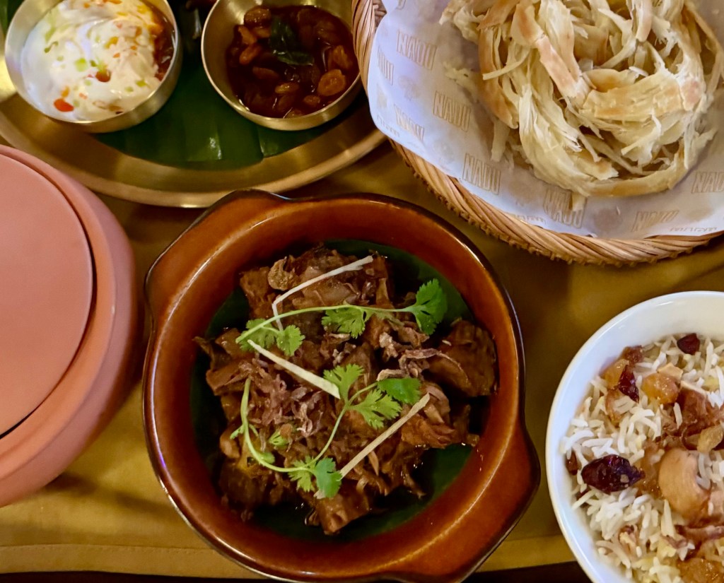 A tray filled with Indian food, including a earthenware bowl of Tender Jack Kosha.