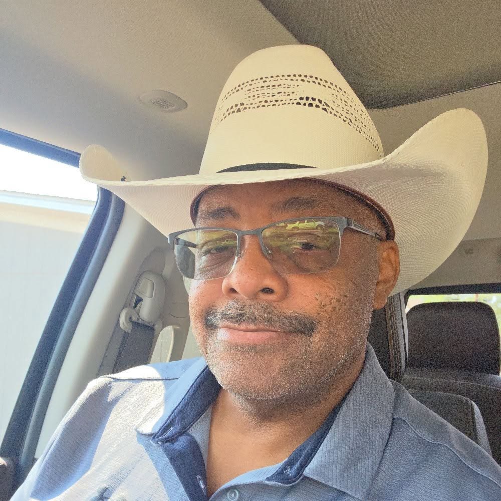 a man in a cowboy hat sits inside a truck