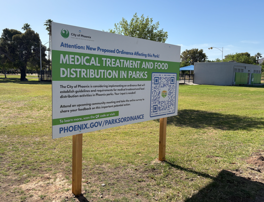 a sign in a park describing phoenix's ban on distributing food or medical aid to people in parks
