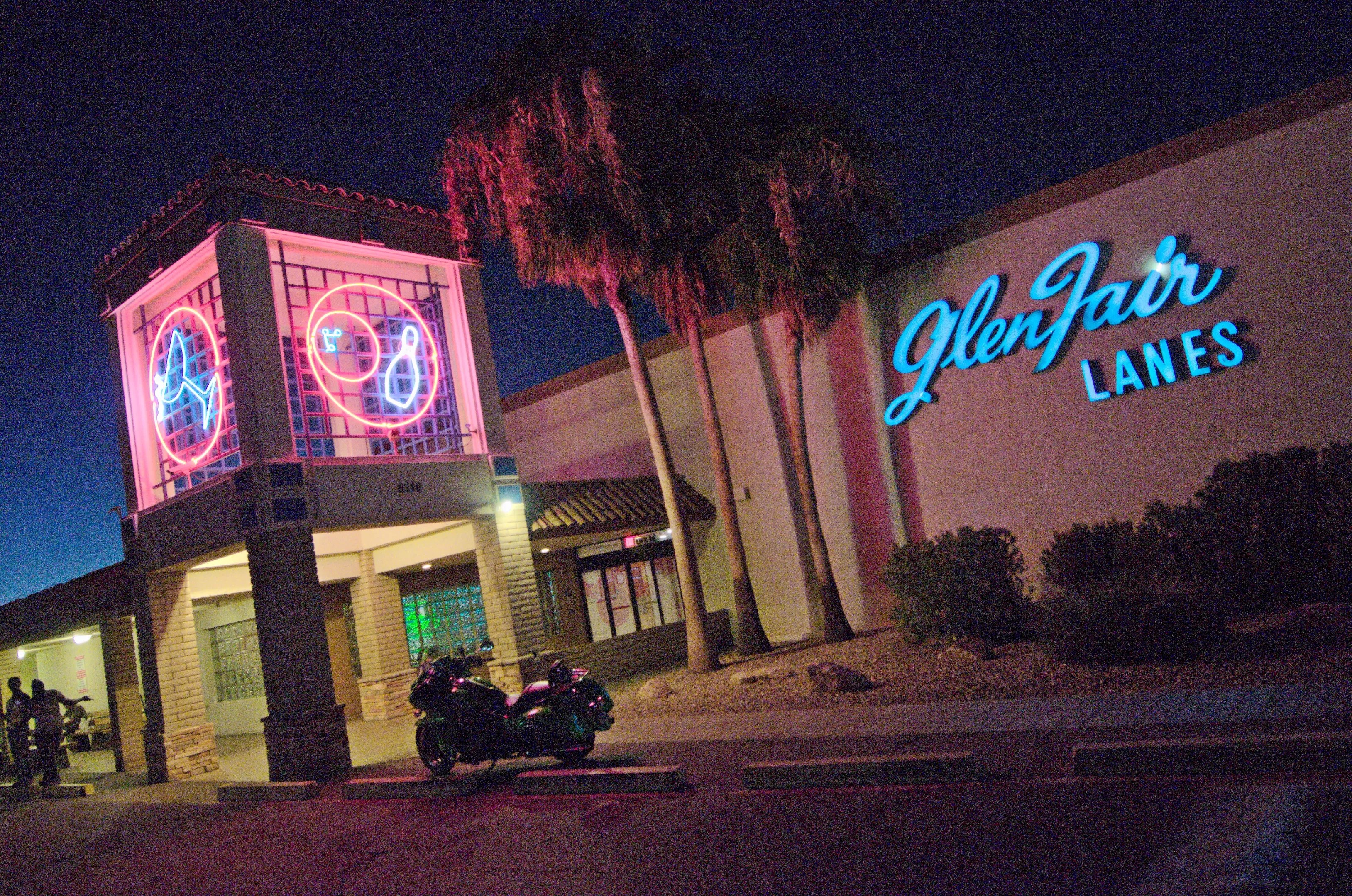 The exterior of a neon-lighted bowling alley at night.