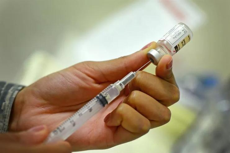 a hand filling a hypodermic needle