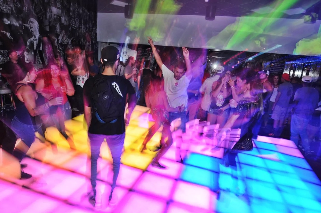 People on a lit-up dance floor.