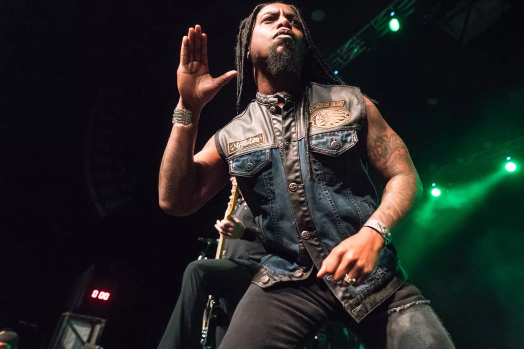 Lajon Witherspoon of Sevendust performs onstage while singing into a microphone during a live concert.