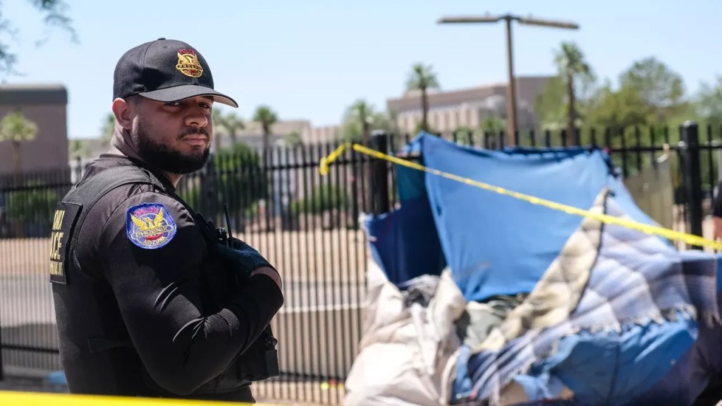 A Phoenix police officer stands in front of a tent d