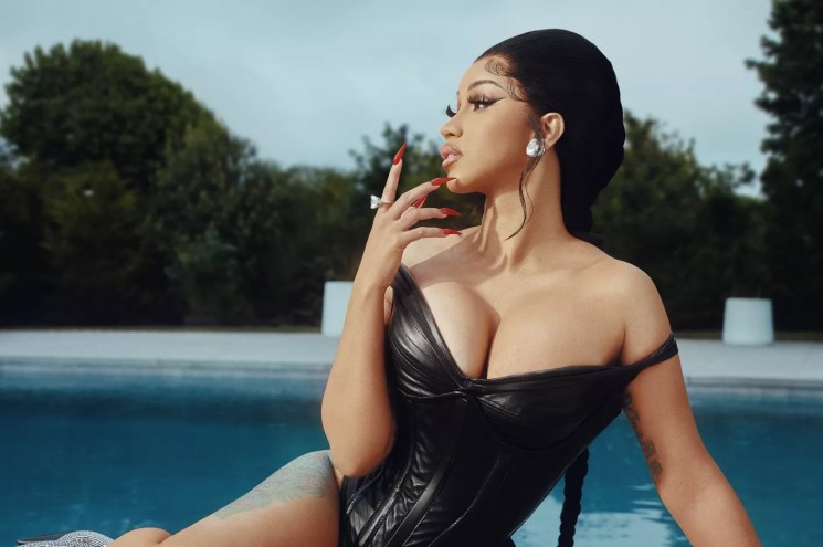 Cardi B in a black dress next to a swimming pool