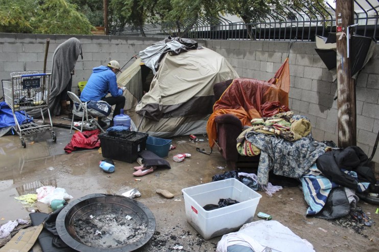 Brian Gruters talks to people living in a dirt lot.