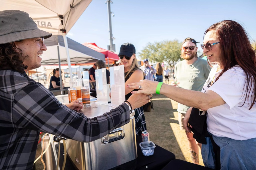 Man hands beer to woman.