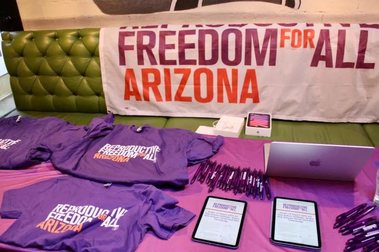 T-shirts, pens and an iPad placed on a table.