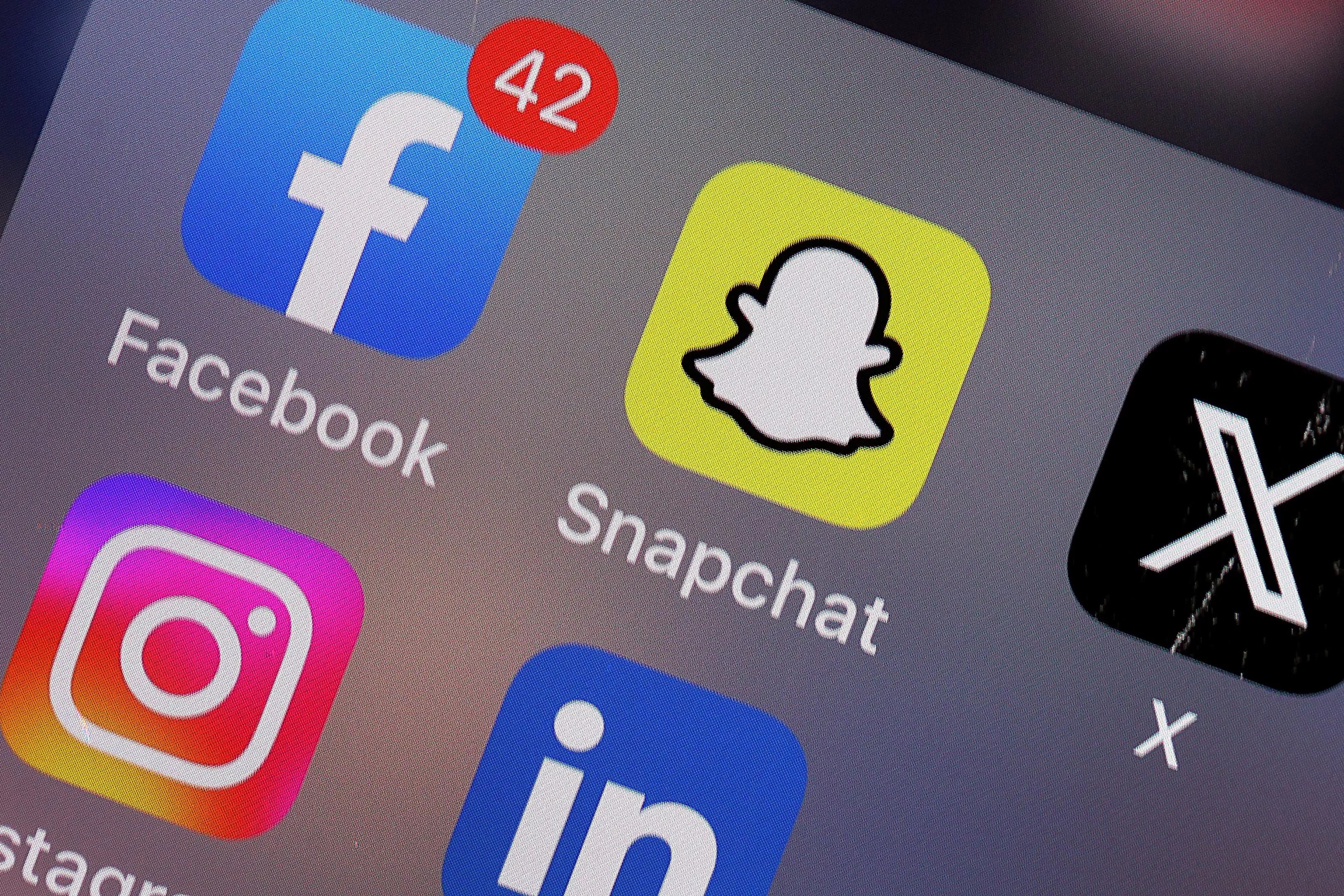 A phone screen with several icons for social media apps like Facebook, Snapchat, Instagram and X.