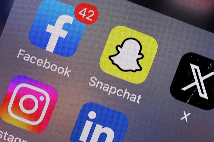 A phone screen with several icons for social media apps like Facebook, Snapchat, Instagram and X.