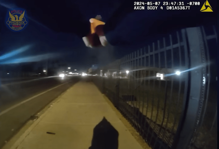 A screenshot from body cam footage showing a police officer's hands gripping a handgun.