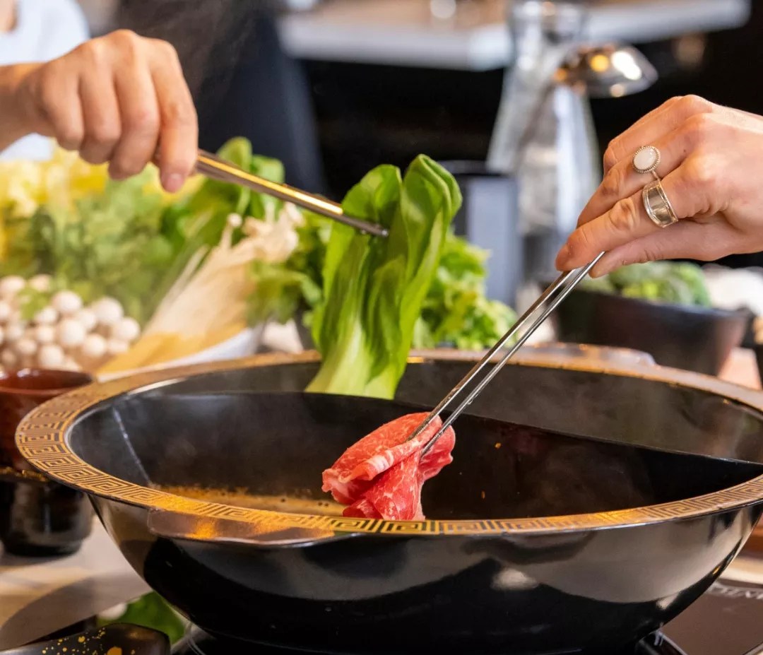 Dipping meat and vegetables into a hot pot.