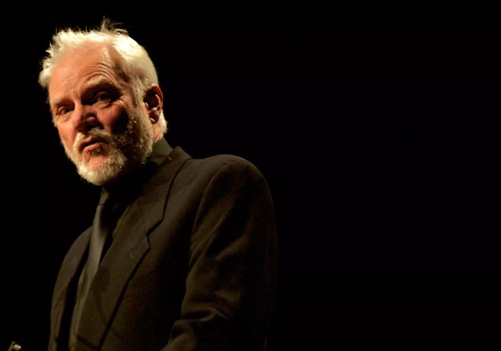 A white haired man wearing black.