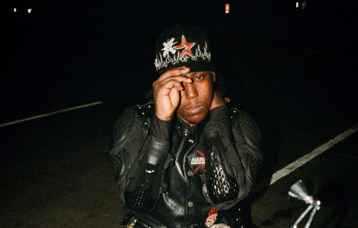 A young Black man posing on a motorcycle.