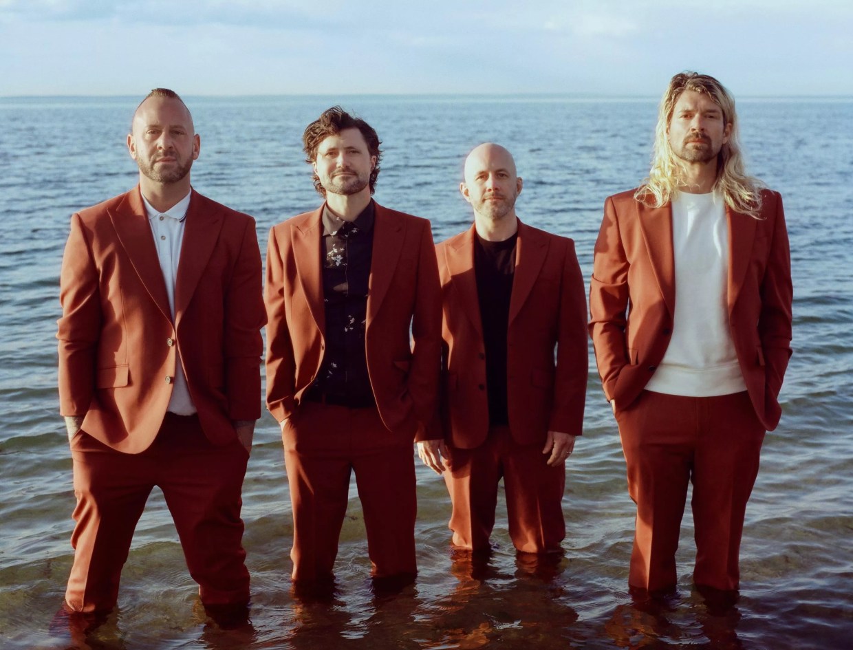 Four men in suits standing in the water.